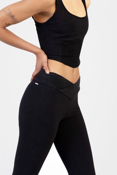 side view of a woman wearing black knit denim pants with a folded waistband and slim fit