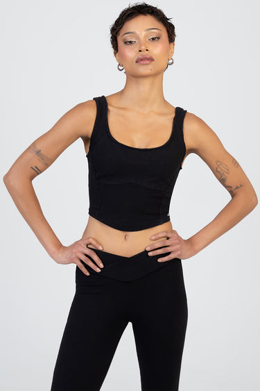 model wearing a black knit cropped tank top with a scoop neck and wide straps, paired with black high waisted leggings