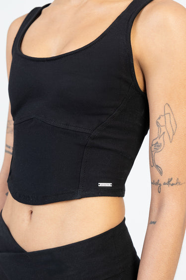 black knit sleeveless cropped top with curved seam and small metal tag at hem