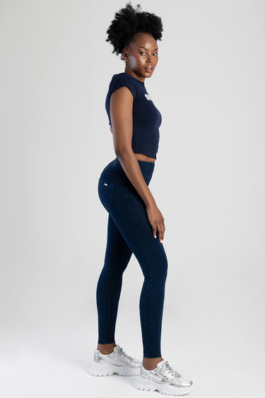 woman in navy knit crop top and dark blue high waist jeans side view with white sneakers