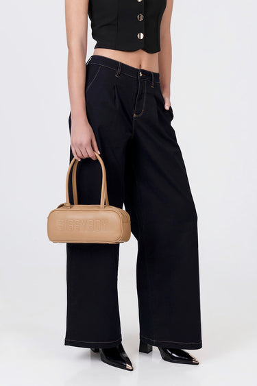 blue jean traders beige bowler bag with twin handles held by a model in black wide leg jeans