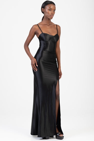 model wearing a black satin corset dress with spaghetti straps, fitted waist and a thigh high slit