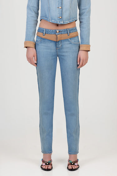 woman wearing light blue jeans with tan waist belt detail and cropped denim jacket, standing in sandals