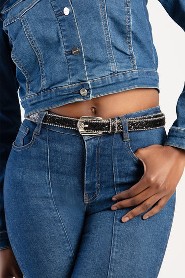 woman wearing a cropped blue denim jacket with matching jeans and a sparkly black and silver belt