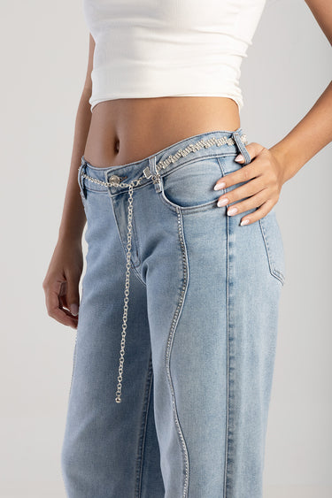 woman wearing light wash jeans with a decorative silver chain belt and beaded trim, white cropped top