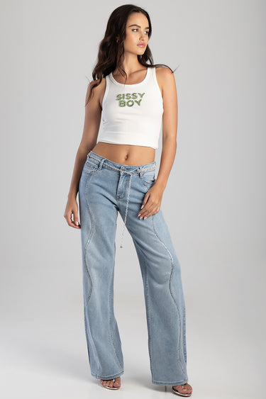 woman in white sleeveless crop top and light wash wide leg jeans with a silver chain belt