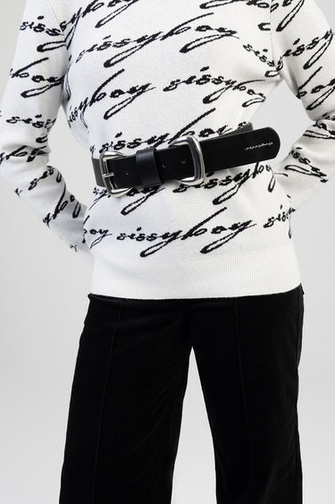 black leather belt with a silver buckle worn over a white knit top with black cursive script pattern