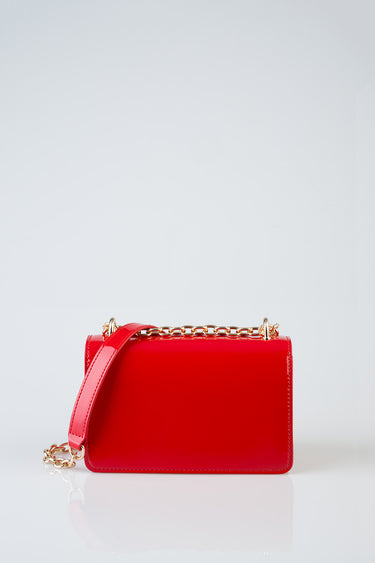 red crossbody bag by Blue Jean Traders with a gold chain strap on a white background