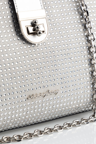 metallic silver tote bag covered in small round studs with a silver chain strap and a cursive logo on the front