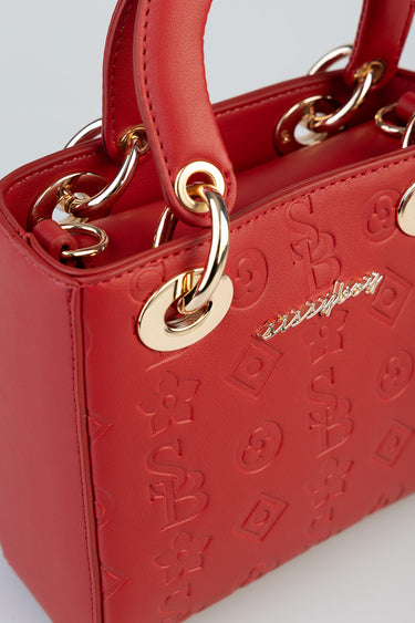 red tote bag with embossed logo pattern and gold hardware on the handles