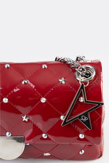 red patent quilted handbag with silver studs and a star charm on a metal chain strap