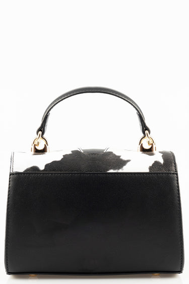 black handbag with a white and black cow print top and gold hardware