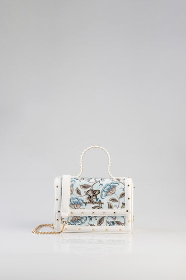 Blue Jean Traders white mini bag with blue floral embroidery, gold studs, pearl top handle and chain strap.