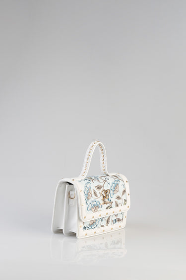 white mini bag with blue floral pattern, gold stud trim, and a top handle