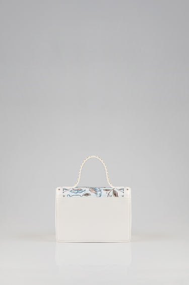 white mini bag with a floral blue top panel and a pearl beaded handle