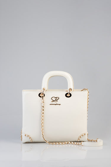 white leather handbag with gold chain strap and two small rounded handles with a decorative metal logo on the front