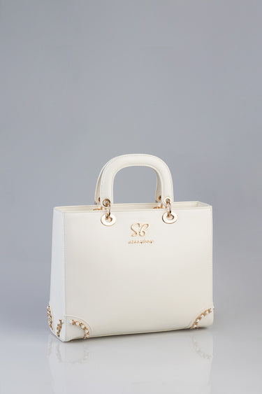 cream structured handbag with two rounded top handles, gold rings, logo emblem, and chain accents at corners