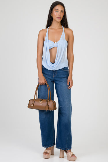 woman in a light blue draped halter top with blue jeans holding a brown handbag and beige platform sandals