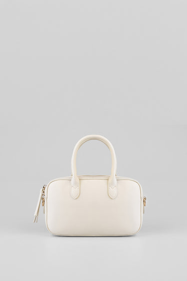 cream white bowler bag with two rounded handles and a gold tone zipper on a plain background