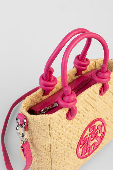 straw handbag with bright pink leather handles and pink circular logo patch, metal zipper and hardware visible