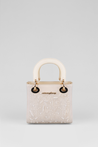 mini handbag in blush pink with white floral embroidery and curved ivory handles
