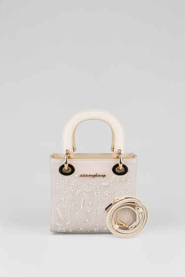 cream mini bag by Blue Jean Traders with floral embroidery and gold ring hardware; includes a detachable strap