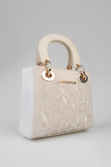 beige mini bag with embroidered floral pattern and pearl beads, white side panels, gold ring hardware and padded top handles