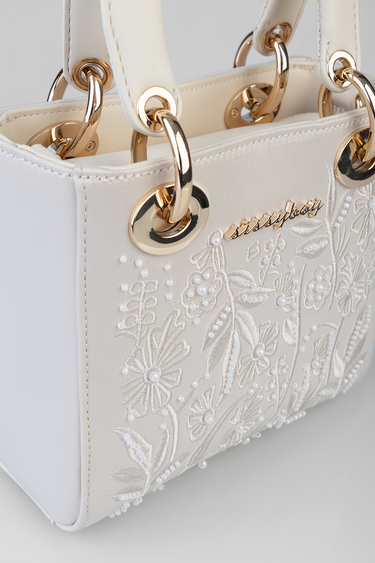 cream mini bag with ivory floral embroidery and pearl beading, gold hardware rings and white handles