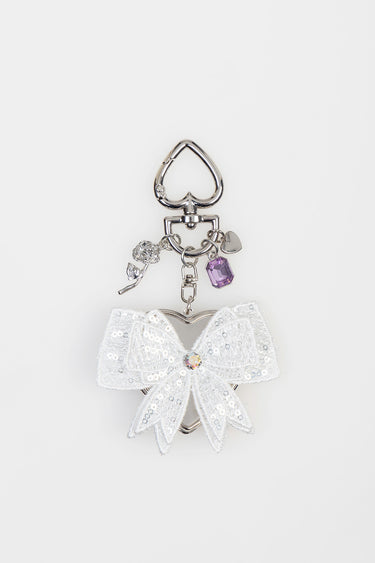 silver keychain charm with white sequin bow and small dangling charms including a rose, purple gem, and heart