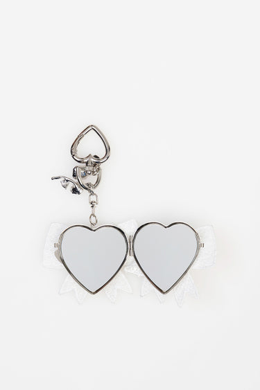 two silver heart shaped mirrored charms connected on a white lace ribbon with a metal clip and chain