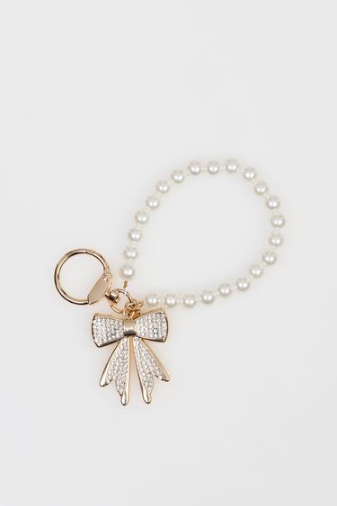 pearl bead bracelet with a gold bow charm encrusted with crystals and a circular ring clasp