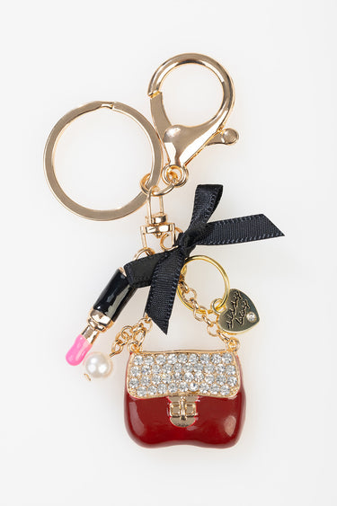 rose gold bag charm featuring a red rhinestone purse, black ribbon bow, pink lipstick bead, pearl bead and heart charm