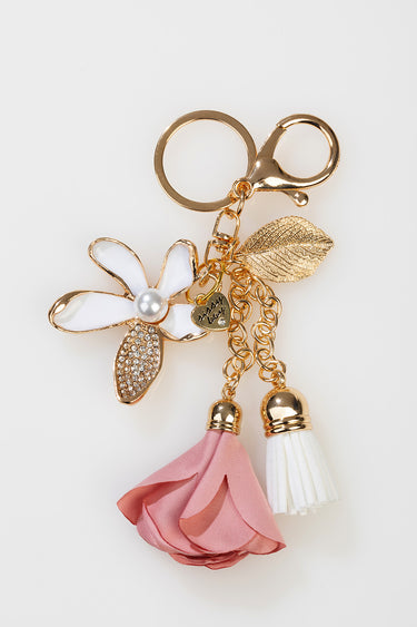 gold tone bag charm featuring a pink fabric flower, white tassels, a rhinestone leaf, and a tiny heart tag