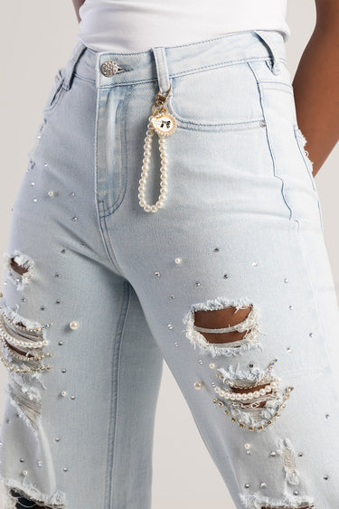 pearls bag charm attached to a belt loop on light denim jeans with a double strand of pearls and a gold heart charm