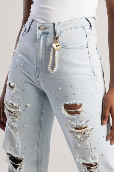 pearl bag charm attached to a light wash jean belt loop with a gold round pendant and pearl strand