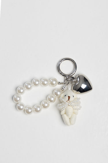 pearl bead bracelet with a small teddy bear charm and a silver heart charm on a metal ring