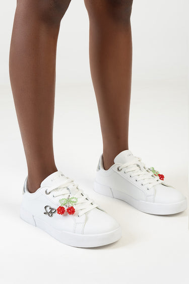 white sneakers with cherry and leaf charms and a small butterfly charm on the left shoe