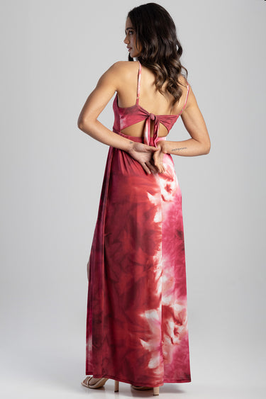 back view of a woman wearing a pink and red tie dye maxi dress with a tied back bow