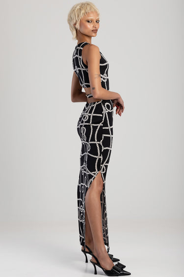model in black and white rope print maxi dress with a crop top and long skirt, side slit, wearing black heels