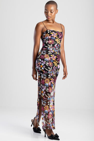 woman in a black maxi dress with colorful floral embroidery, spaghetti straps, fitted silhouette and sheer overlay with a