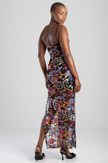 woman wearing a black sheer floral maxi dress with thin straps, back view.