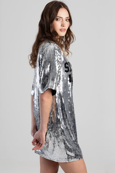 woman wearing a silver sequin short sleeve dress with a relaxed fit and side slit