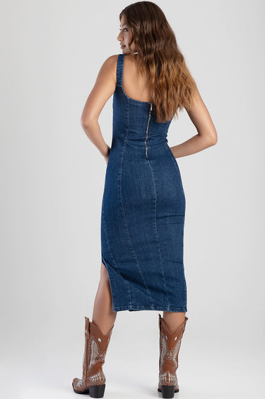 woman in a blue denim midi dress with a back zipper, sleeveless, standing in brown cowboy boots
