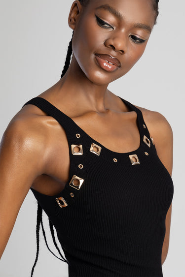 woman in black ribbed knit sleeveless top with gold square stud accents along the straps