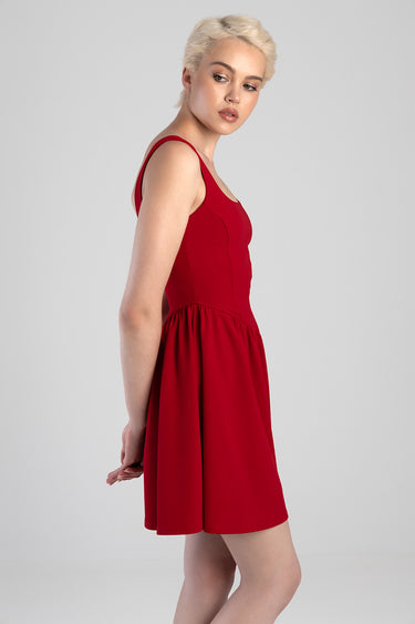 woman wearing red sleeveless mini dress with a gathered waist, side profile view.