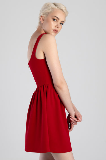 model with short blonde hair wearing a red sleeveless mini dress with a gathered waist in profile