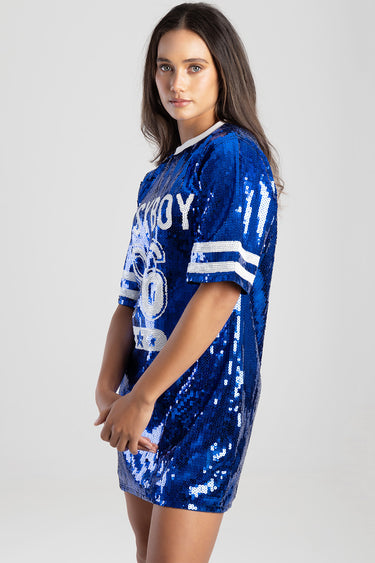 woman wearing a royal blue sequin dress with white graphic print and striped sleeve cuffs