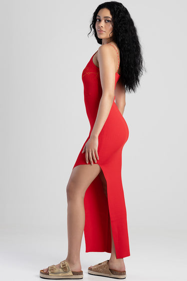 side view of a woman in a red knit dress with a high side slit and thin straps, wearing tan sandals