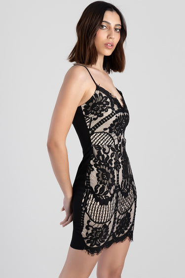 woman in a black lace mini dress with floral panels and spaghetti straps, side view