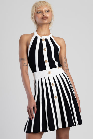 model wearing black and white striped knit dress with halter neck, gold buttons down the front, white waistband, and